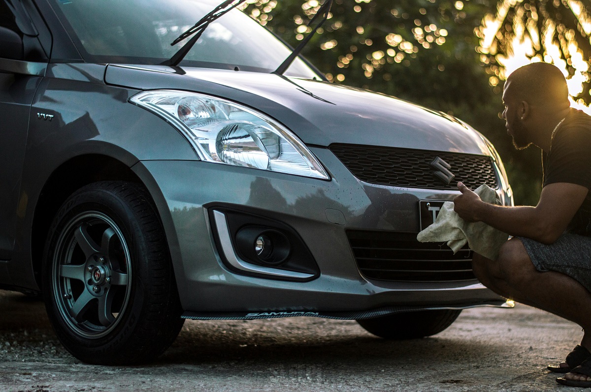 man cleaning his gray car, with the wipers lifted