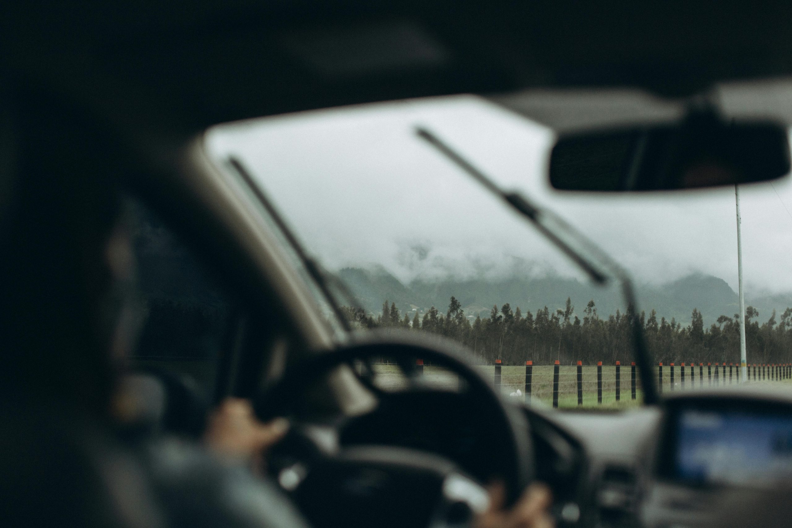 man driving on a scenic road while using wipers